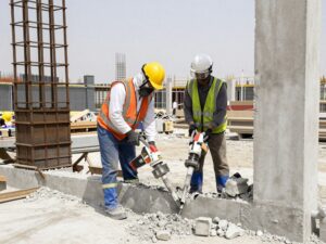عمال يقومون بتكسير خرسانة باستخدام معدات ثقيلة